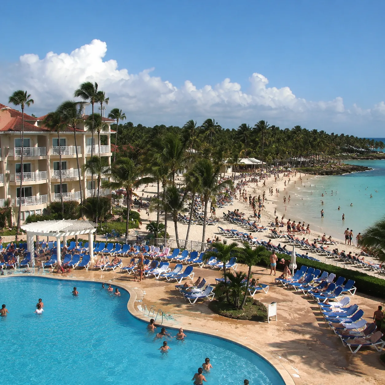 Square editorial travel photo of a dated beachfront all-inclusive resort in Bayahibe Dominican Republic, busy pool chair