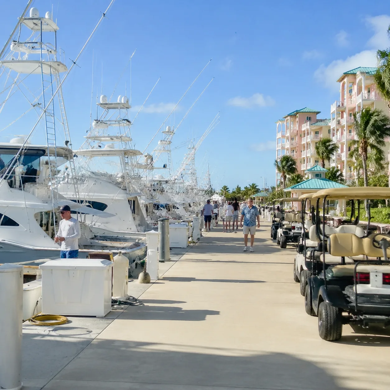 Busy marina in Bimini Bahamas with sport fishing boats, golf carts, resort buildings, bright flat sunlight