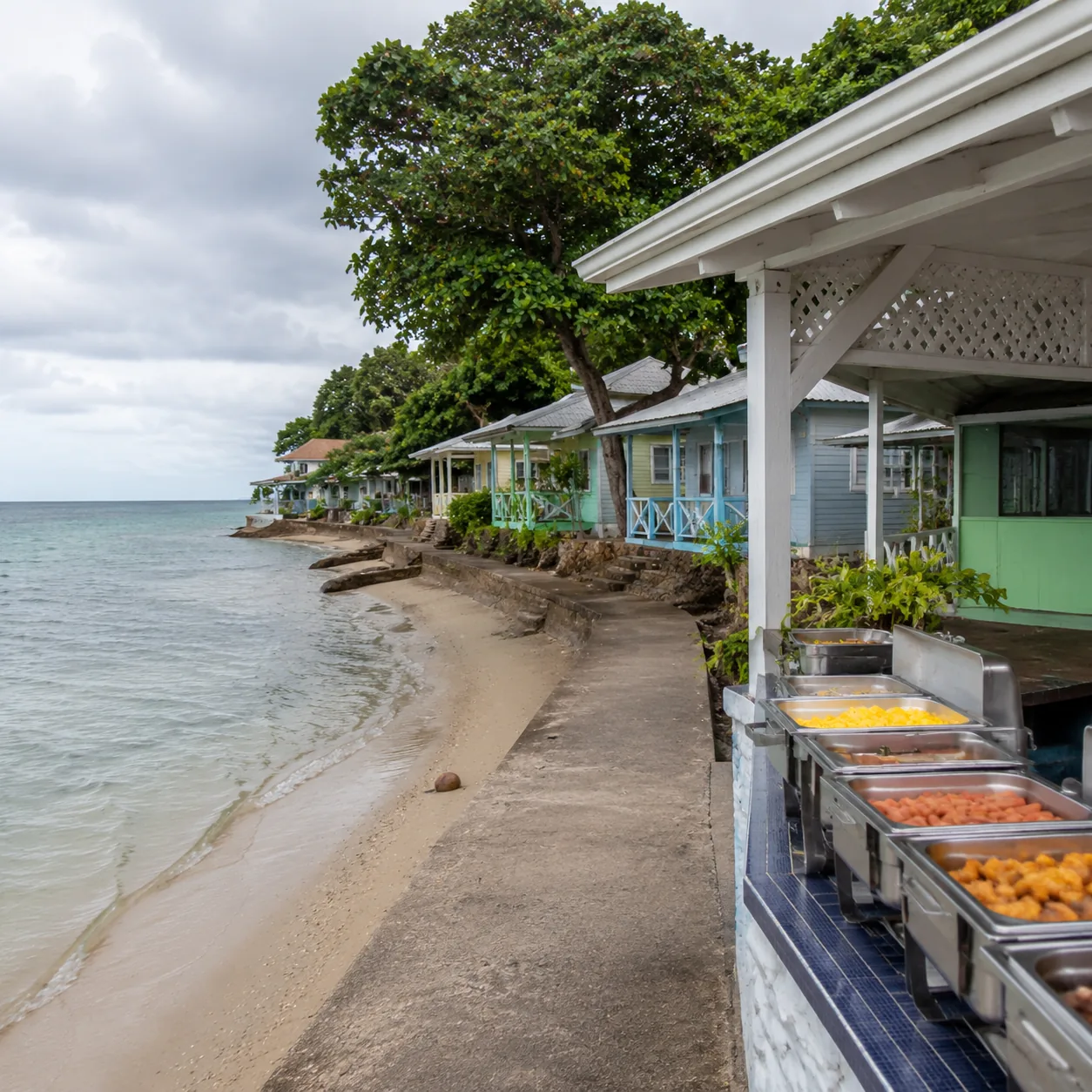 Square editorial travel photo of a budget Jamaica beach resort with small cottages, narrow beach, simple buffet terrace,