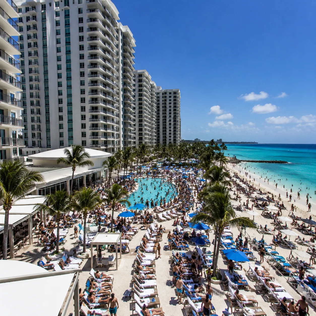 Square travel photo of a tall beachfront Bahamas all-inclusive beside crowded resort towers, busy narrow pool deck, gues