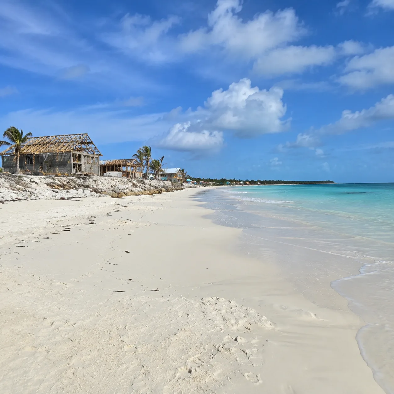 Treasure Cay beach on Great Abaco Bahamas with wide pale sand, rebuilding signs, quiet shoreline, clear water