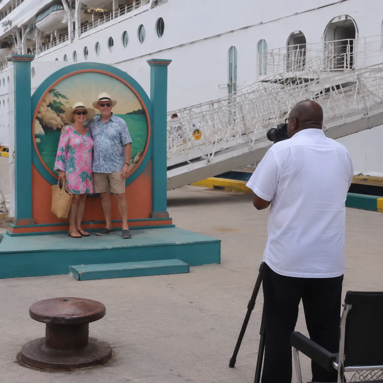 Realistic editorial photo of cruise passengers gathered around an excursion sign near a port bus, backpacks and sun hats