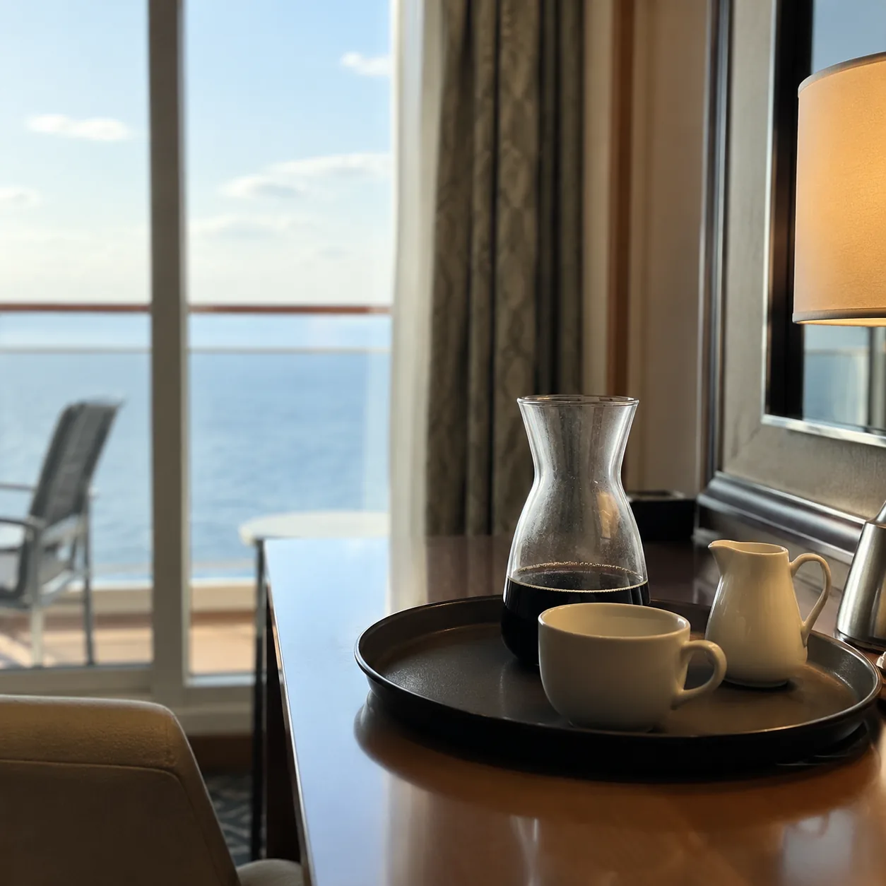Realistic editorial photo of a cruise cabin breakfast tray with coffee, pastries, and fruit on a small balcony table, mo