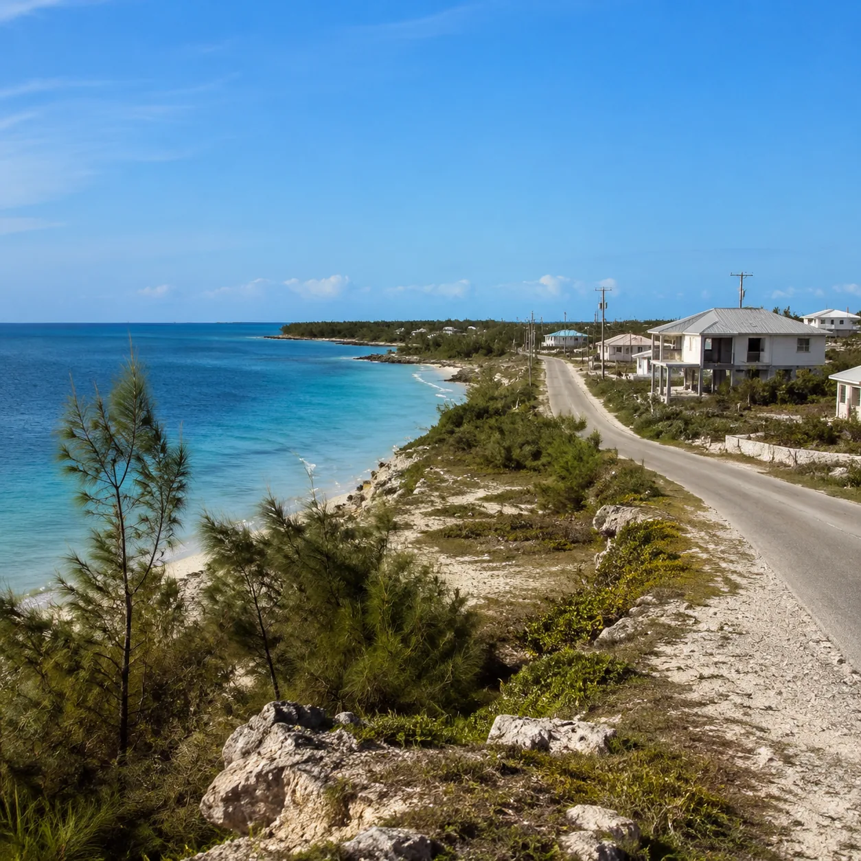 Great Abaco Bahamas quiet coastline with rebuilding homes, pine trees, blue water, practical island road