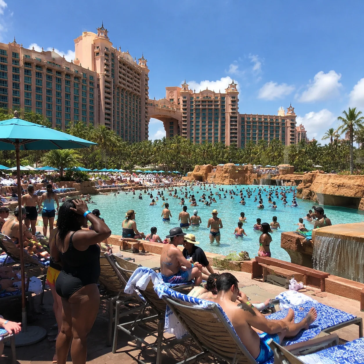 Massive Atlantis Paradise Island resort towers in Nassau Bahamas, crowded waterpark pools and beach chairs below, famili