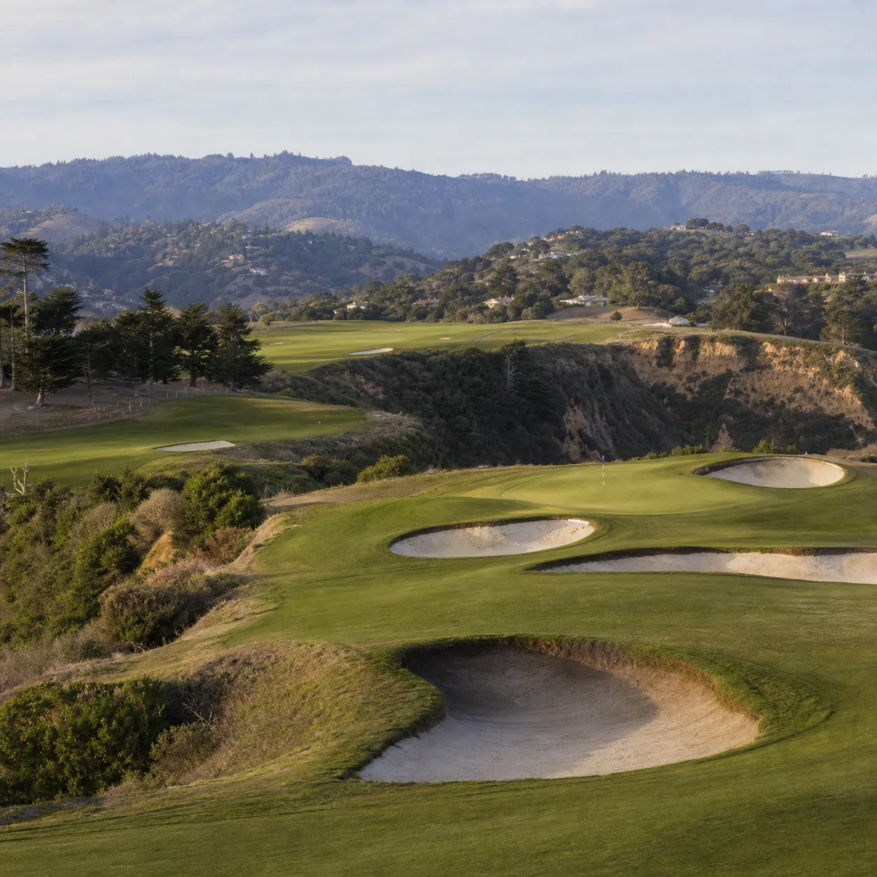 Realistic editorial photo of a classic California hillside golf course with deep bunkers, rolling green, barranca edge,