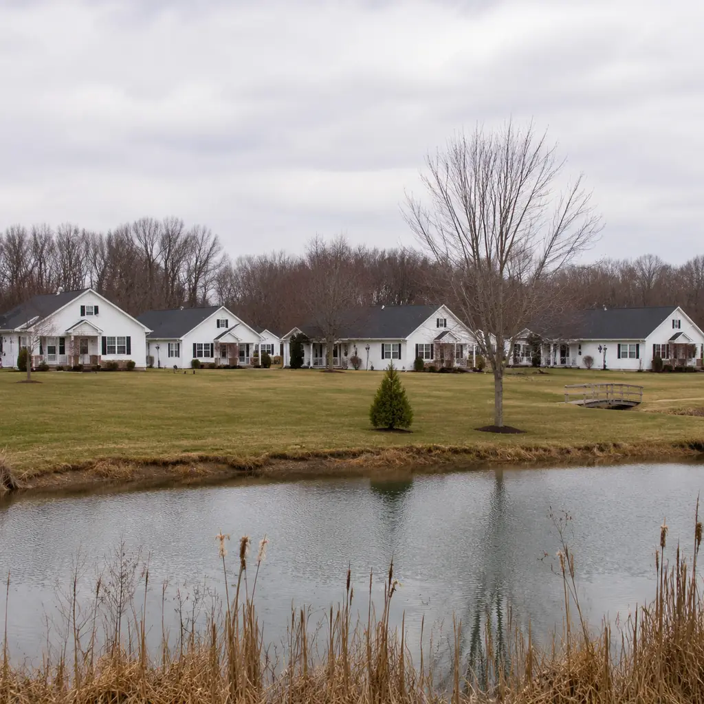 Realistic editorial photo of a small town Ohio retirement community with white cottages, black shutters, open lawn, pond