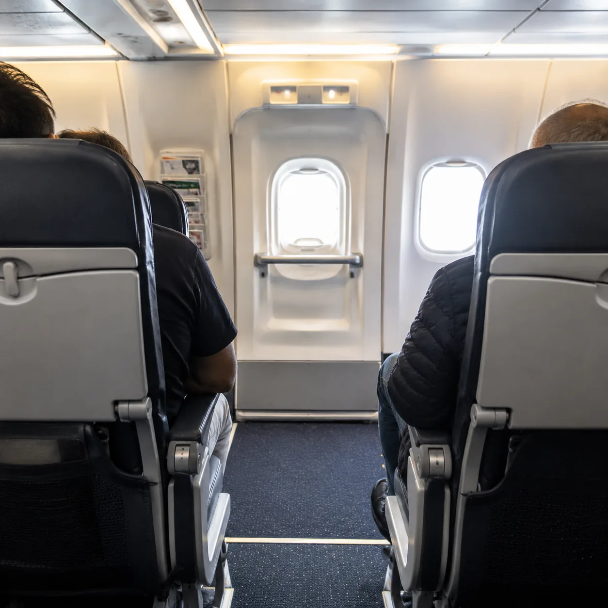 Realistic editorial photo of a standard economy seat row directly ahead of an airplane exit row, realistic editorial pho