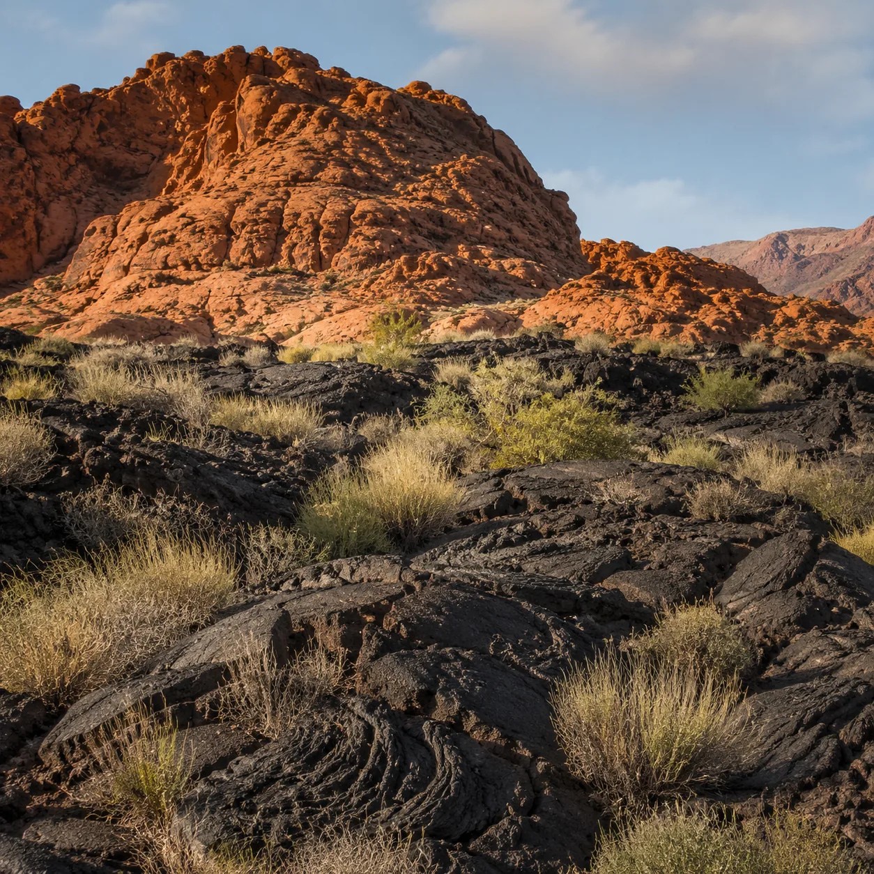 Realistic editorial photo of red sandstone cliffs and black lava rock in Snow Canyon State Park Utah, warm natural trave