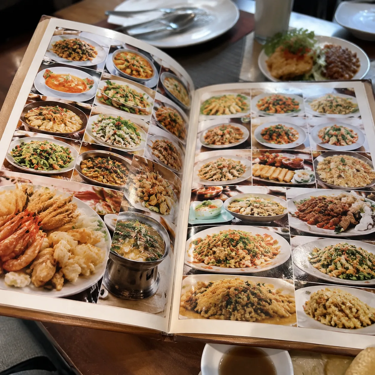 Realistic editorial photo of an oversized tourist restaurant menu showing many different dish categories on a table with